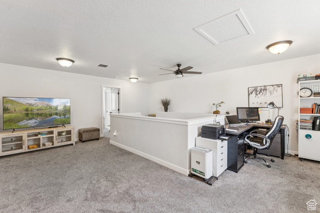 Carpeted office space with attic access and a ceiling fan
