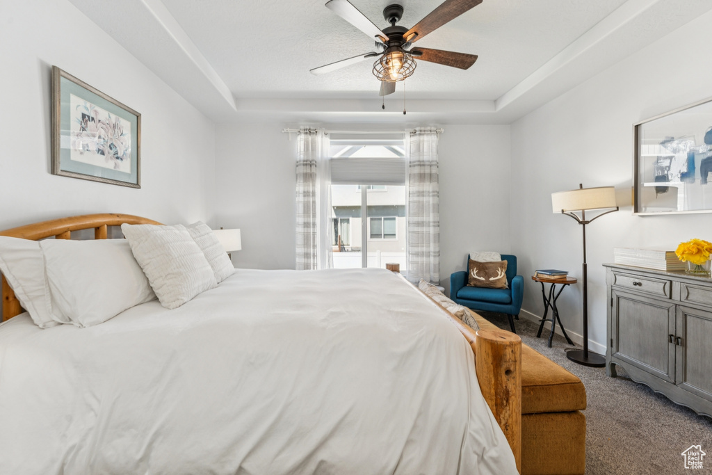 Carpeted bedroom with a raised ceiling and a ceiling fan