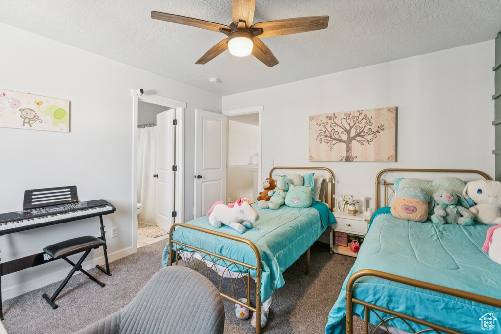 Carpeted bedroom with a textured ceiling, ensuite bathroom, and ceiling fan