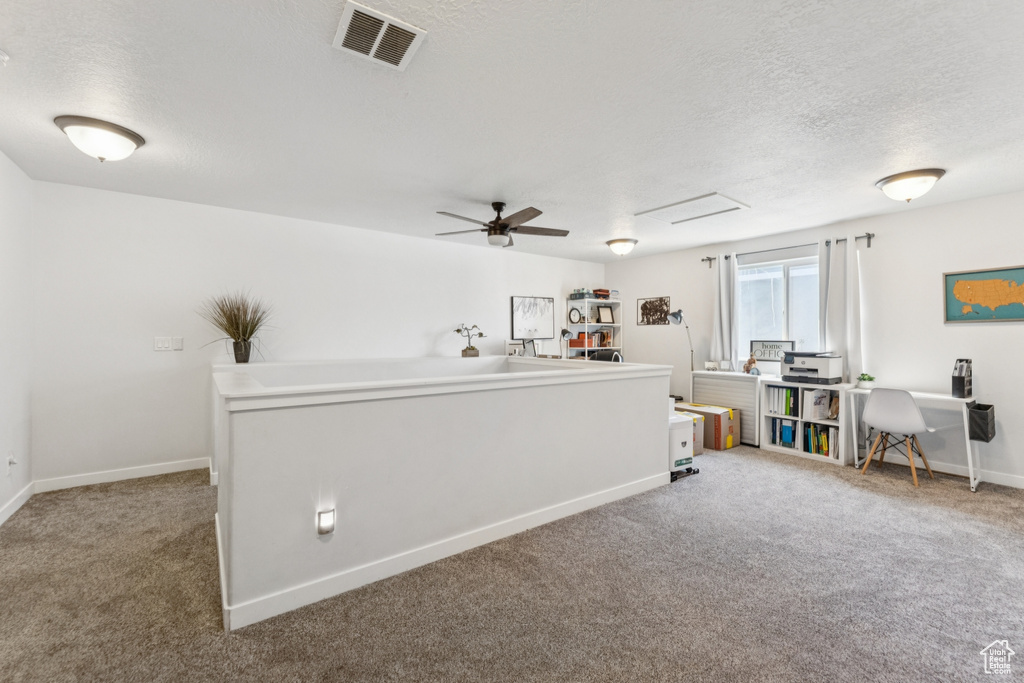 Carpeted home office featuring a textured ceiling and a ceiling fan