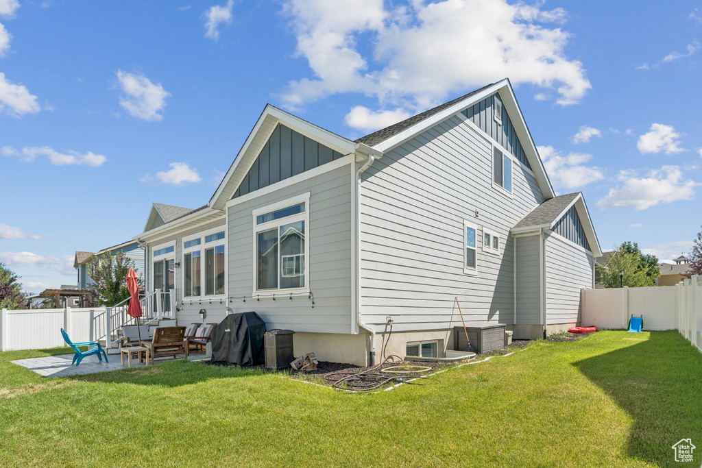 Rear view of property with board and batten siding, a fenced backyard, and a patio area