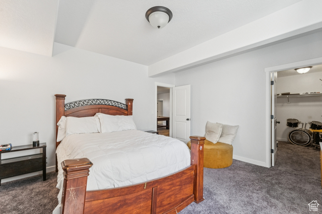Carpeted bedroom featuring a walk in closet and baseboards
