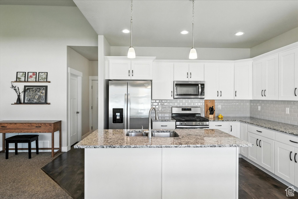Kitchen featuring appliances with stainless steel finishes, tasteful backsplash, light stone countertops, white cabinetry, and recessed lighting