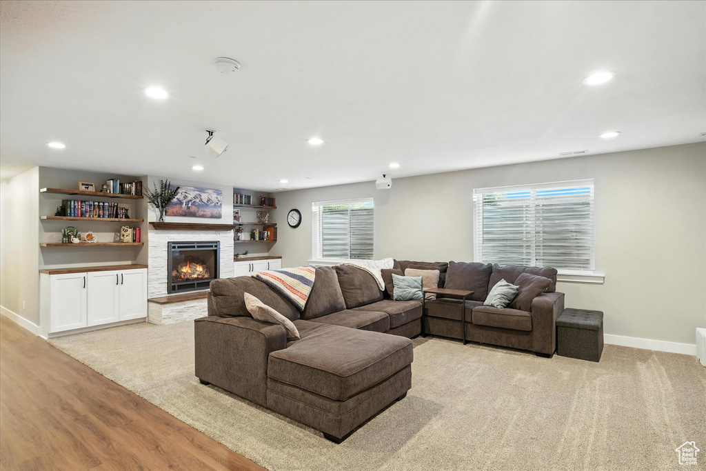 Living area featuring recessed lighting, light wood-style flooring, and a warm lit fireplace