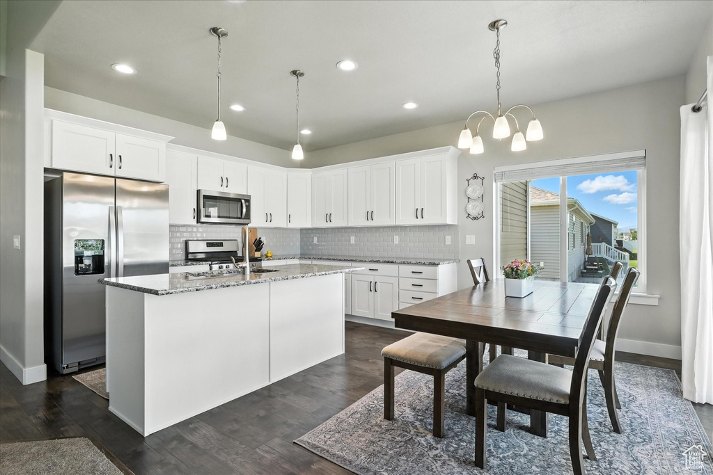 Kitchen featuring appliances with stainless steel finishes, backsplash, light stone countertops, white cabinetry, and recessed lighting