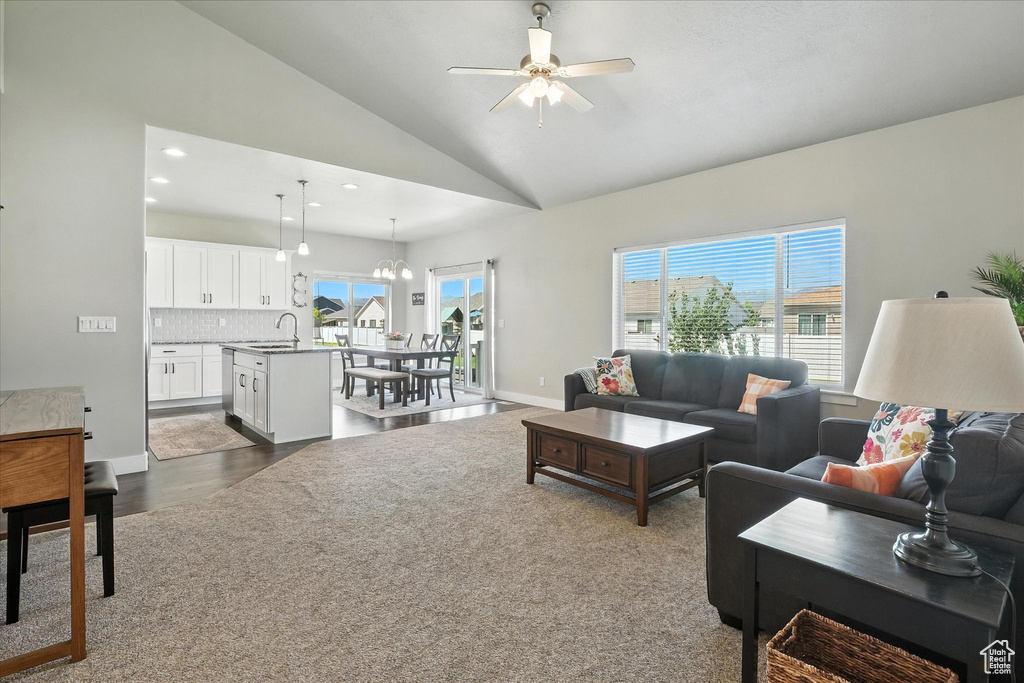 Living room featuring lofted ceiling, ceiling fan, recessed lighting, a chandelier, and dark wood finished floors
