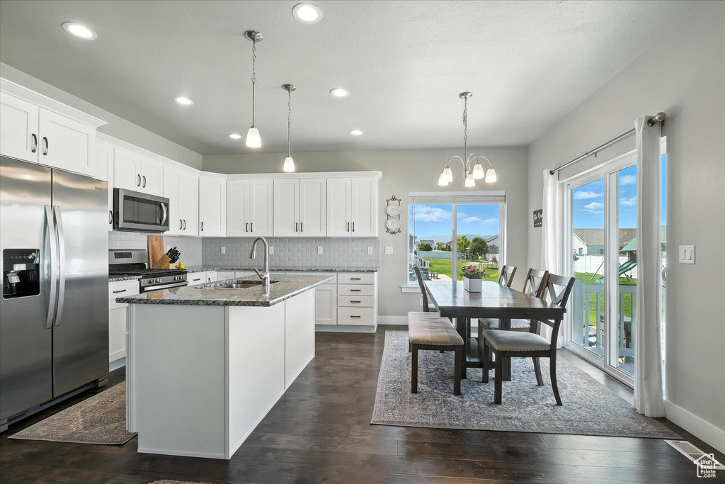 Kitchen with stainless steel appliances, decorative backsplash, dark wood finished floors, white cabinetry, and recessed lighting