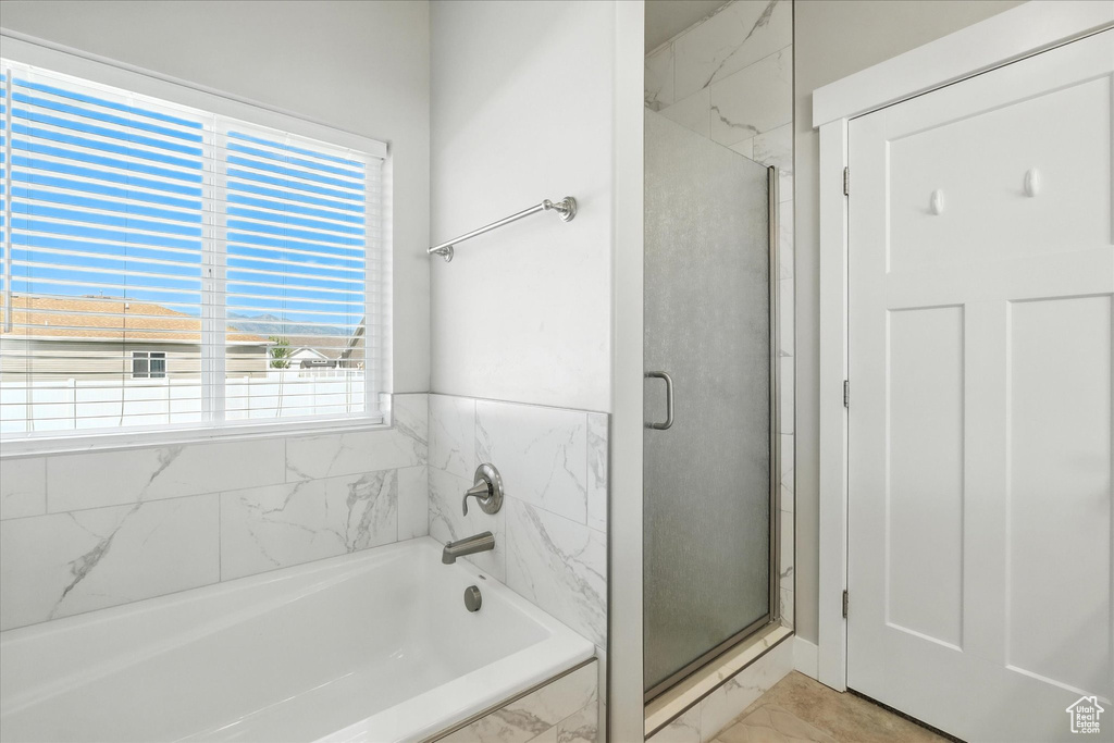 Bathroom featuring marble look tile flooring, a bath, and a shower stall