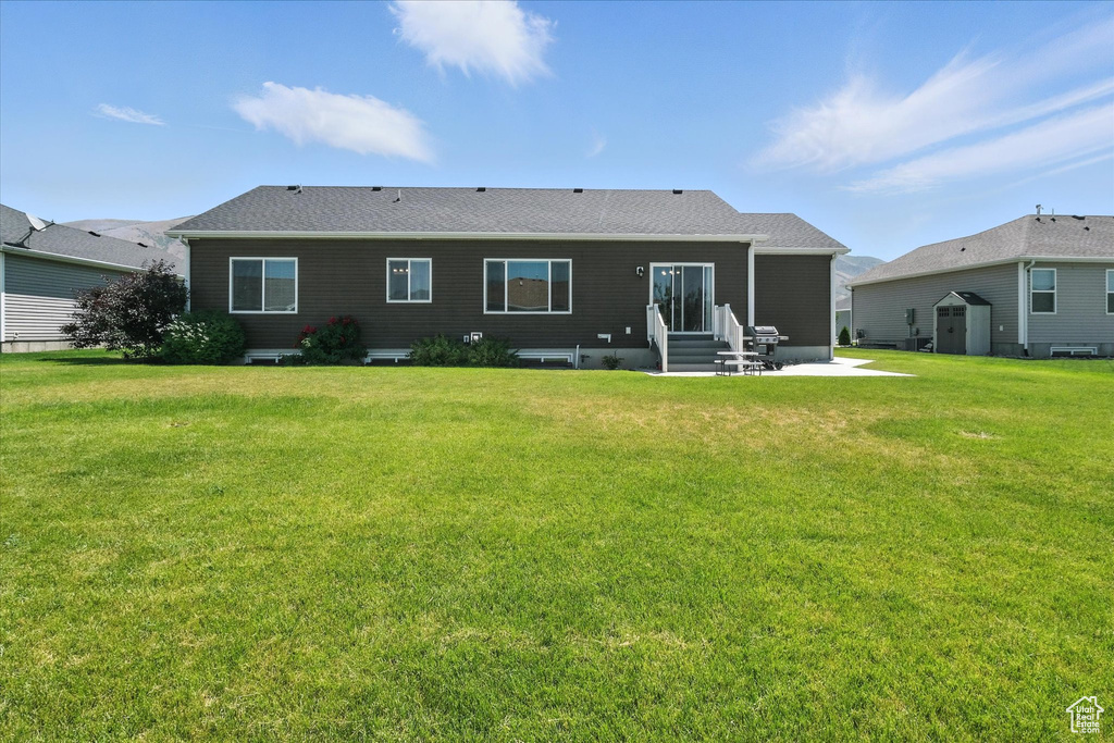 Back of house featuring entry steps, a shed, a patio, and a yard