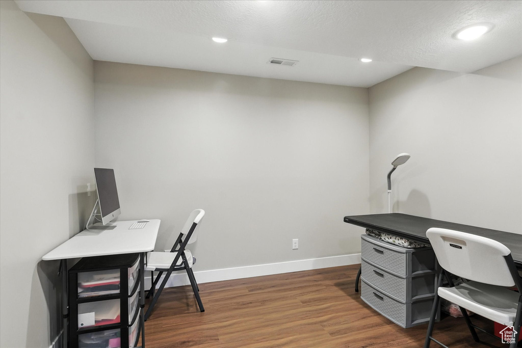 Office space with dark wood-type flooring and recessed lighting