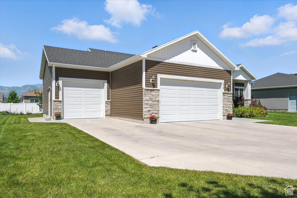 View of front of property with stone siding, driveway, an attached garage, and board and batten siding
