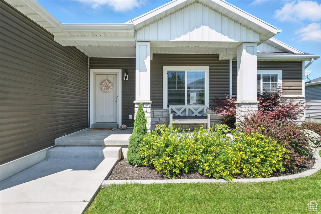 View of exterior entry with board and batten siding and a porch