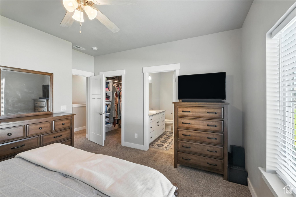 Carpeted bedroom with a spacious closet, ensuite bath, and ceiling fan