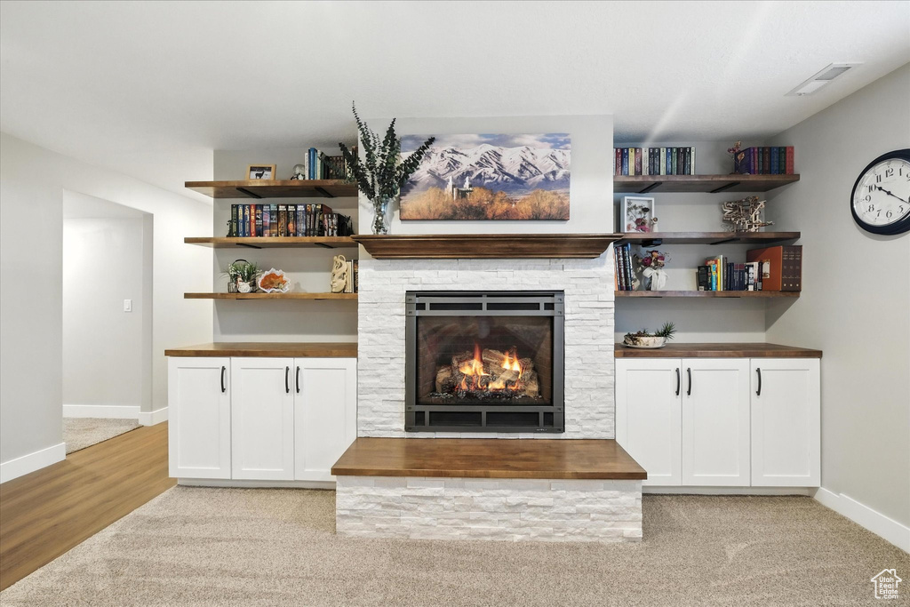 Unfurnished living room with a stone fireplace and light colored carpet