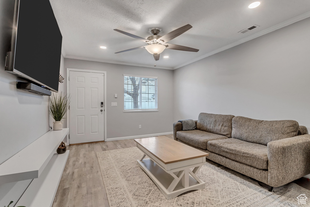 Living area featuring ceiling fan, ornamental molding, light wood-style flooring, and recessed lighting