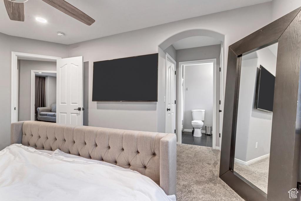 Bedroom with carpet, arched walkways, and connected bathroom