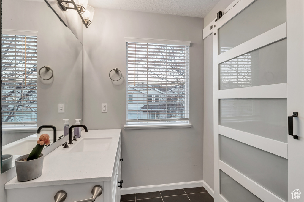Bathroom featuring tile patterned flooring, plenty of natural light, and vanity
