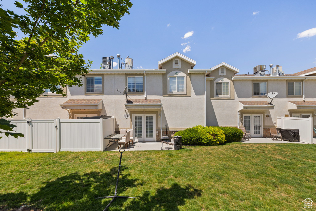 Rear view of property with french doors, a gate, a fenced backyard, and stucco siding