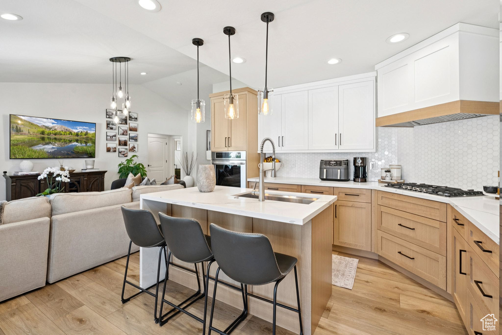 Kitchen with appliances with stainless steel finishes, open floor plan, lofted ceiling, light wood-style floors, and recessed lighting