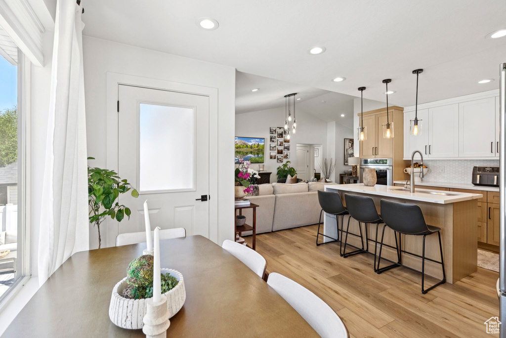 Dining area with vaulted ceiling, healthy amount of natural light, light wood finished floors, and recessed lighting