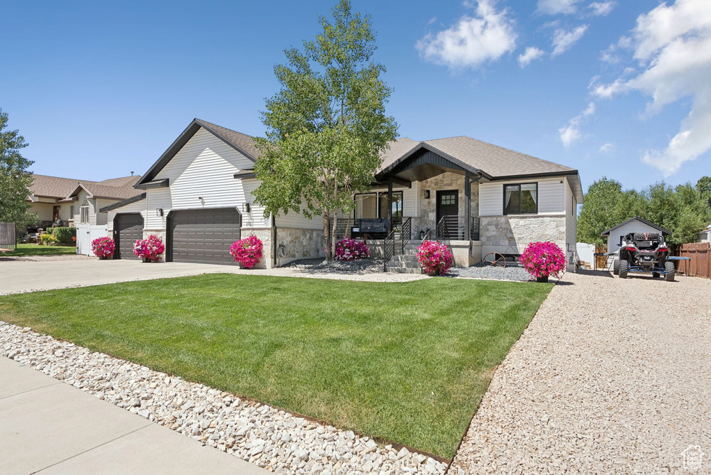 View of front of home with stone siding, a front lawn, concrete driveway, and a garage