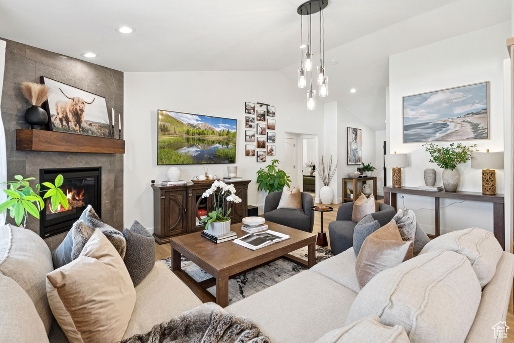 Living area with a fireplace, recessed lighting, high vaulted ceiling, and wood finished floors