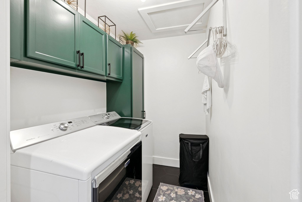 Laundry room with cabinet space, independent washer and dryer, and dark tile patterned flooring