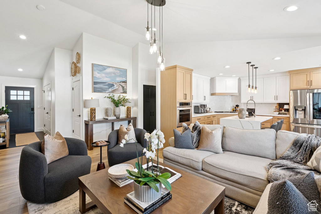 Living room with vaulted ceiling, recessed lighting, and light wood-style flooring