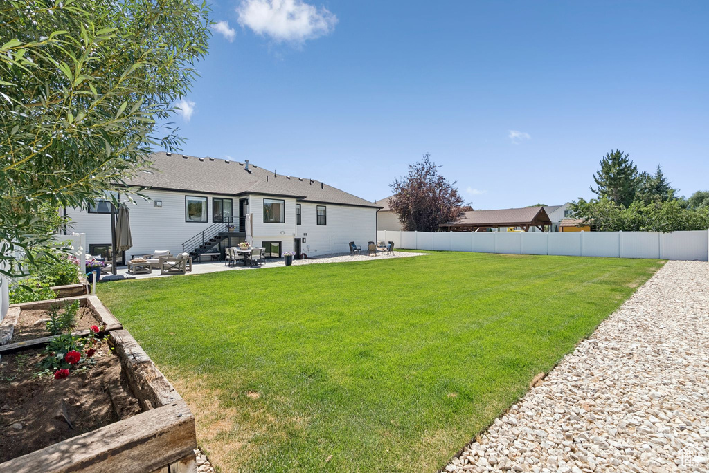Rear view of property with a patio, a fenced backyard, and roof with shingles