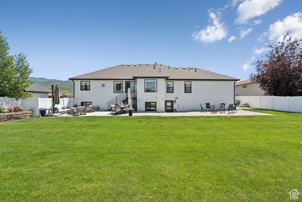 Back of property featuring a patio, an outdoor living space, a fenced backyard, and roof with shingles