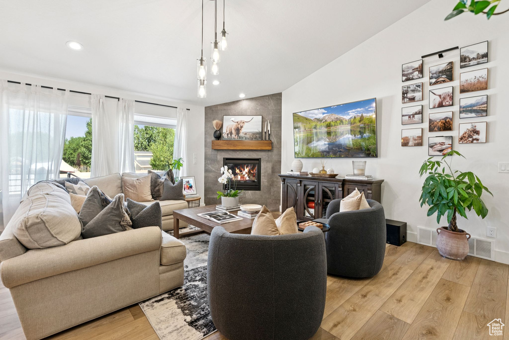 Living room with light wood-style floors, a fireplace, recessed lighting, and vaulted ceiling