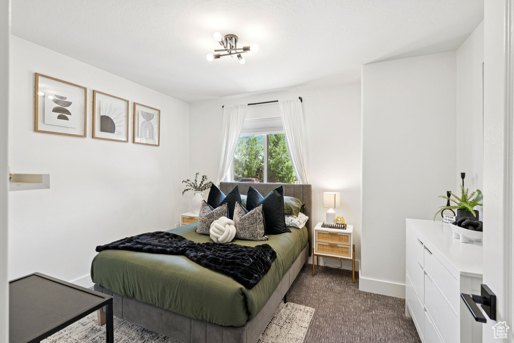 Bedroom with a chandelier and dark colored carpet