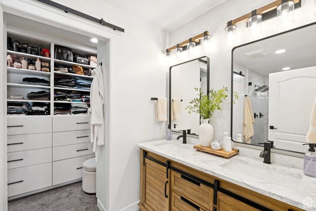 Full bathroom with double vanity, a shower, and a spacious closet