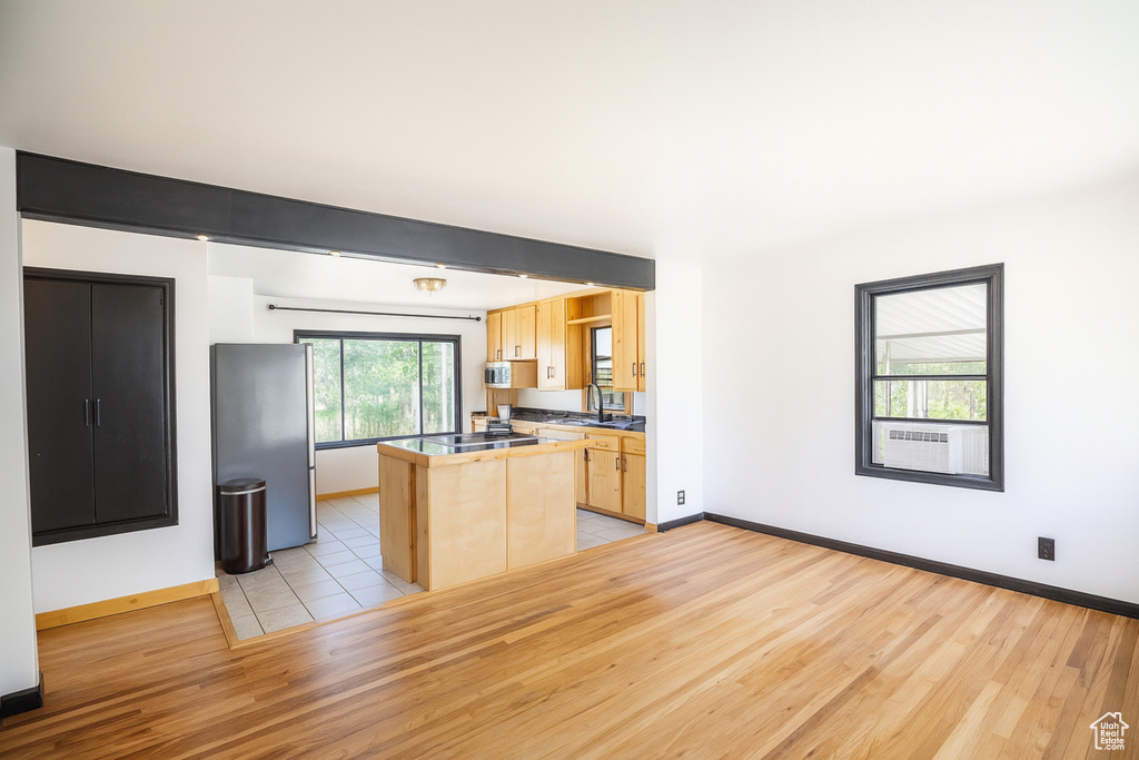 Kitchen featuring light brown cabinets, light wood-style floors, stainless steel appliances, and a kitchen island