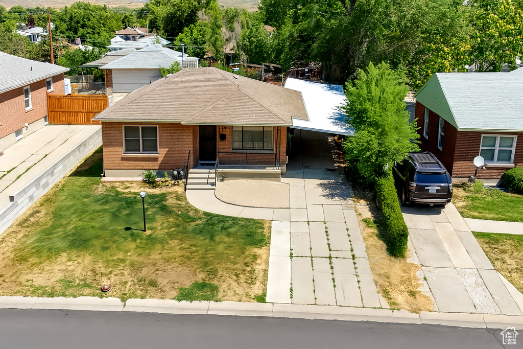 View of front of property with driveway, brick siding, an attached carport, roof with shingles, and a porch