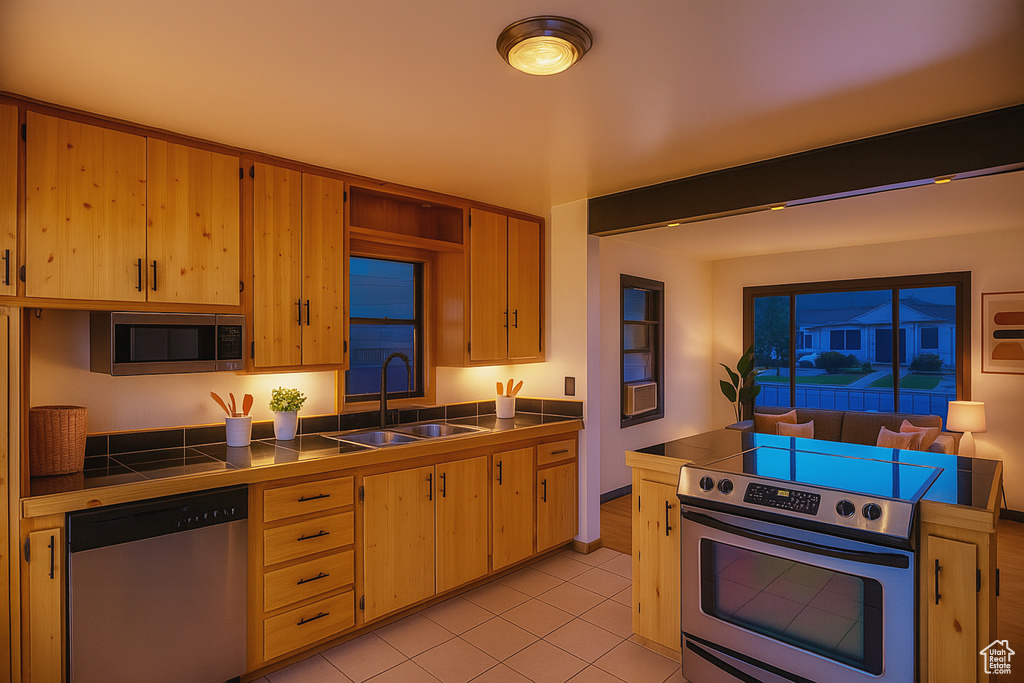 Kitchen with stainless steel appliances, tile counters, and light tile patterned floors