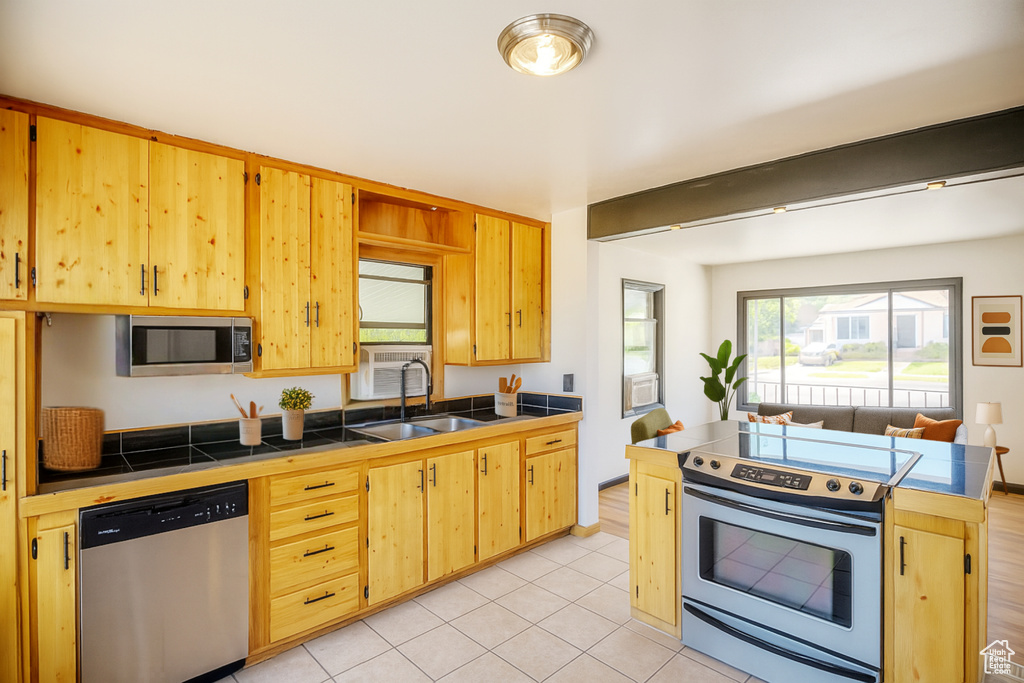Kitchen featuring appliances with stainless steel finishes, tile counters, and light brown cabinets