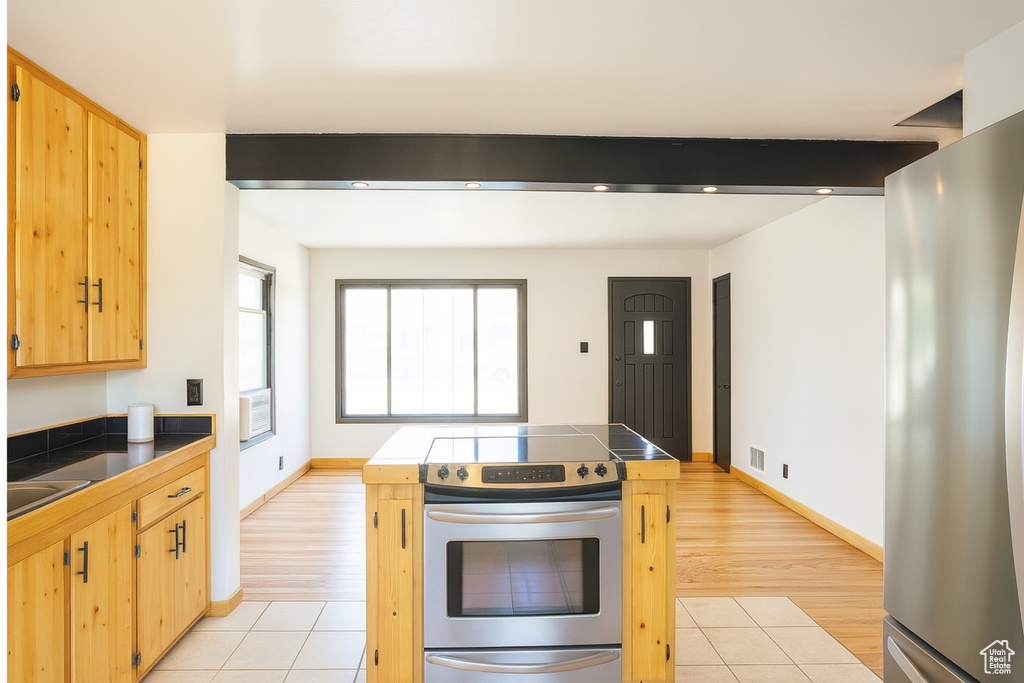 Kitchen featuring stainless steel appliances, tile countertops, light brown cabinetry, and light tile patterned floors