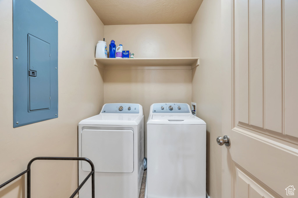 Laundry area featuring electric panel, independent washer and dryer, and a textured ceiling