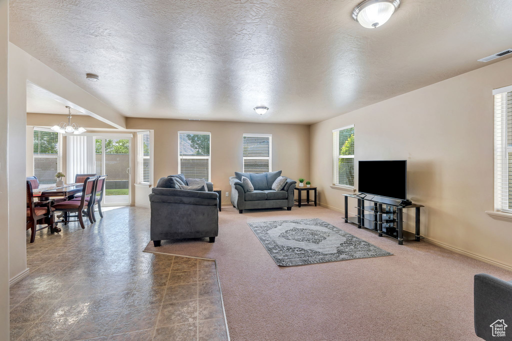 Living area featuring a chandelier, healthy amount of natural light, and a textured ceiling