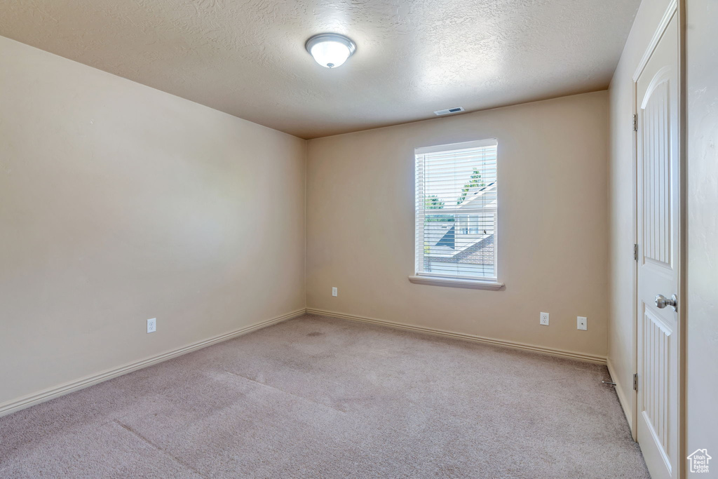 Spare room featuring carpet and a textured ceiling