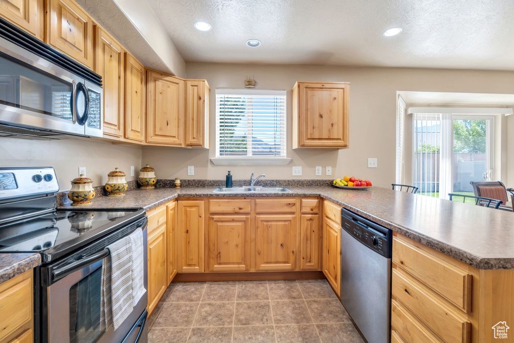 Kitchen with stainless steel appliances, a peninsula, light brown cabinets, healthy amount of natural light, and recessed lighting