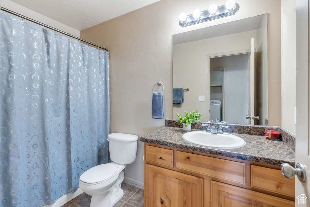 Full bath featuring vanity, washer / dryer, tile patterned flooring, and a shower with curtain