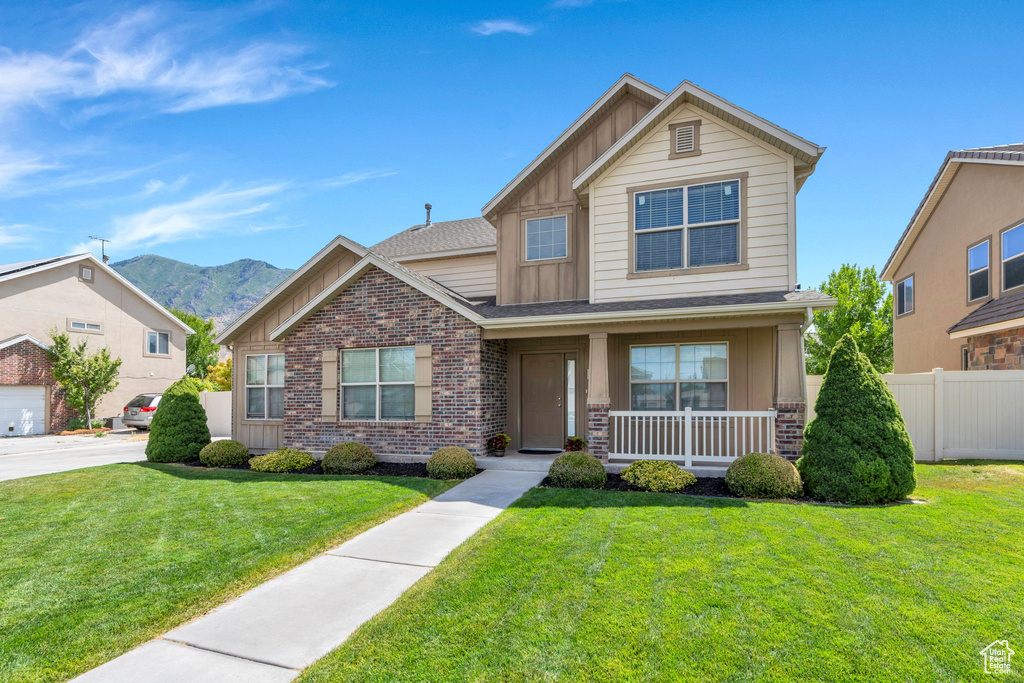 View of front of home featuring board and batten siding, covered porch, a mountain view, and brick siding