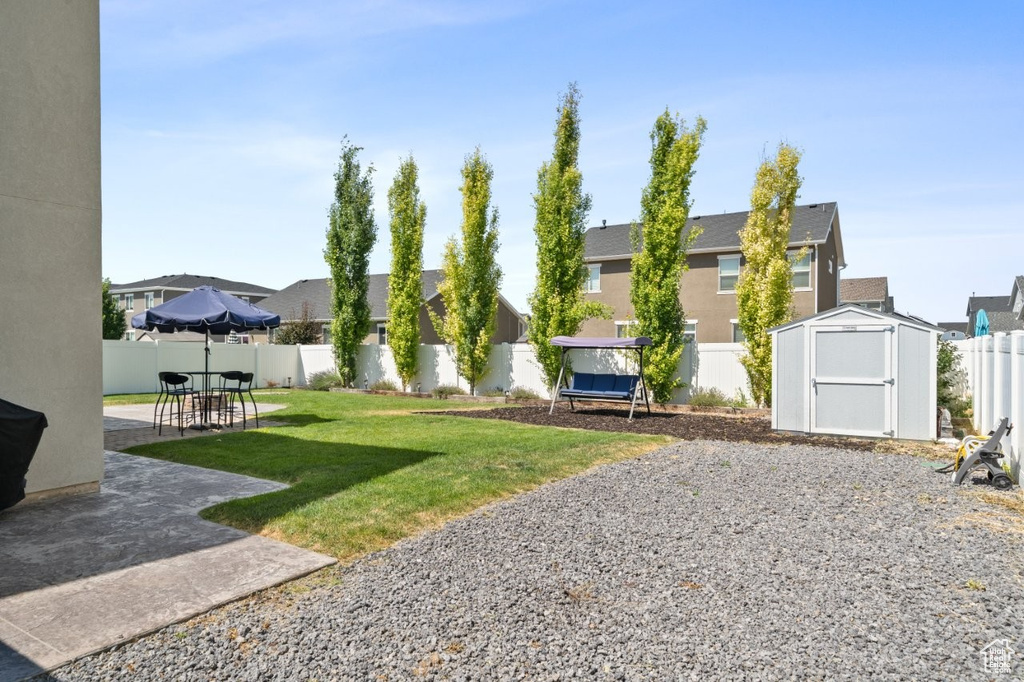 Fenced backyard featuring a patio, a shed, and a residential view