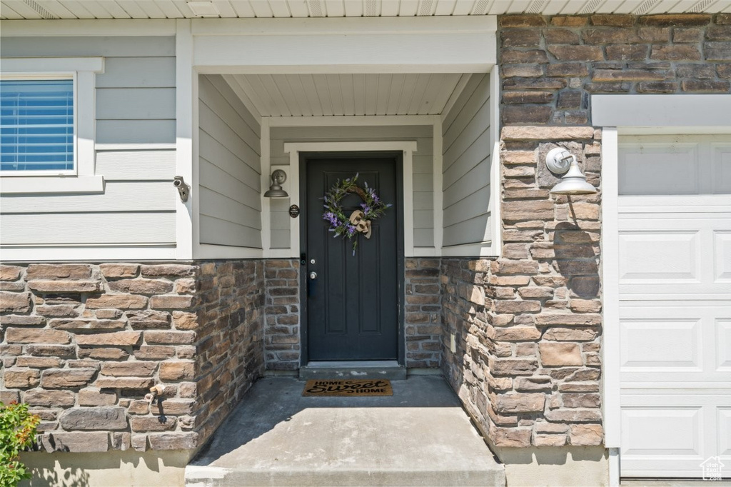 Doorway to property with stone siding and a garage