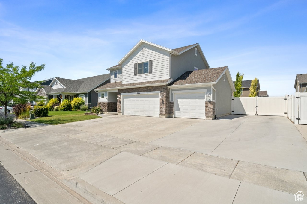 View of front of house with a gate, driveway, stone siding, and a garage