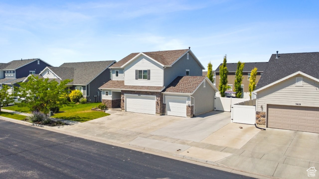 View of front of property featuring a gate, driveway, a residential view, and an attached garage