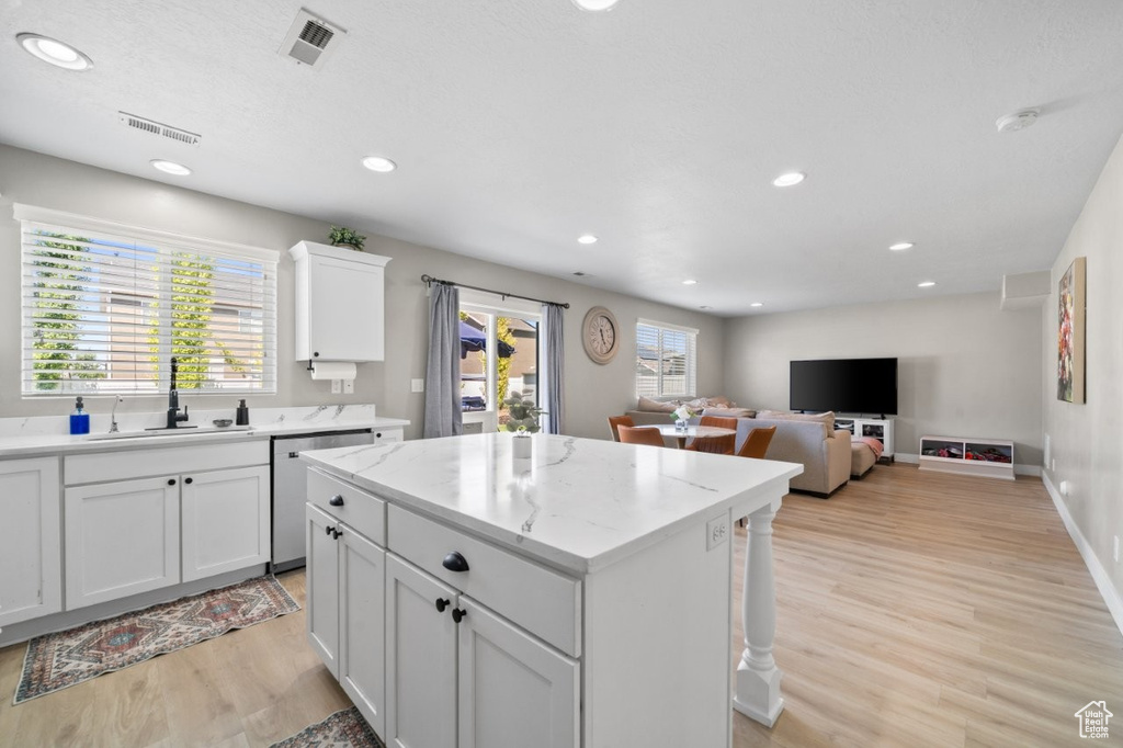 Kitchen featuring stainless steel dishwasher, light wood-style flooring, a kitchen island, recessed lighting, and white cabinetry