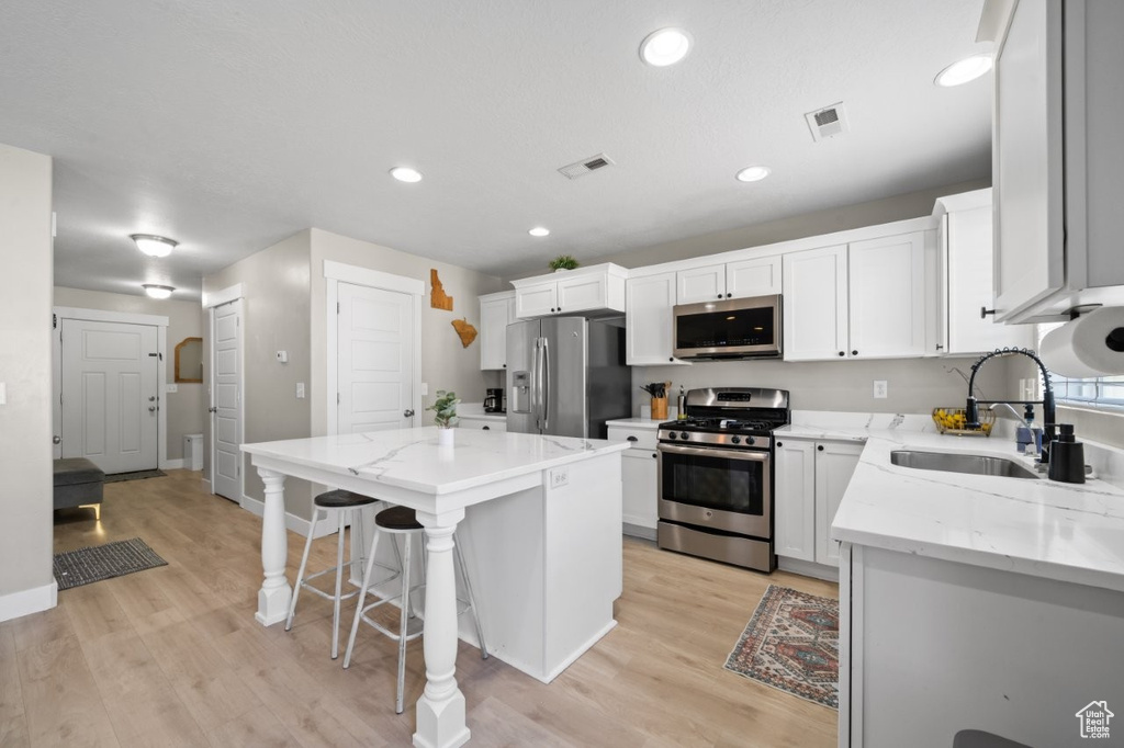 Kitchen featuring appliances with stainless steel finishes, a center island, light wood-style floors, a kitchen breakfast bar, and recessed lighting